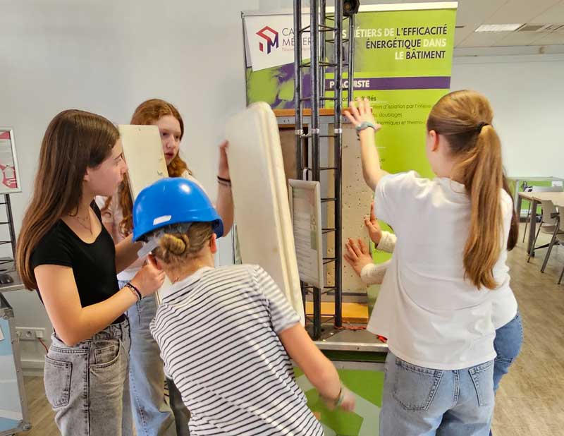 Des jeunes manipulent des panneaux isolants lors d’un atelier interactif de l’exposition sur les métiers de l’efficacité énergétique dans le bâtiment.