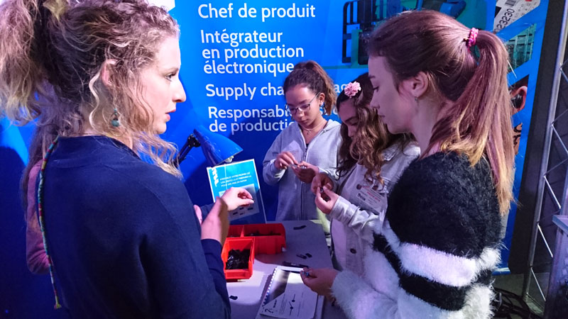 Un groupe de jeunes assemble une pièce mécanique lors d’un atelier de l’exposition sur les métiers de l’industrie.
