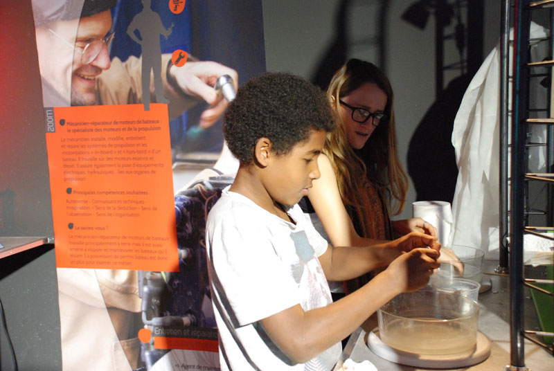 Un jeune participe à un atelier pratique autour de la mécanique nautique lors d’une exposition sur les métiers du nautisme.