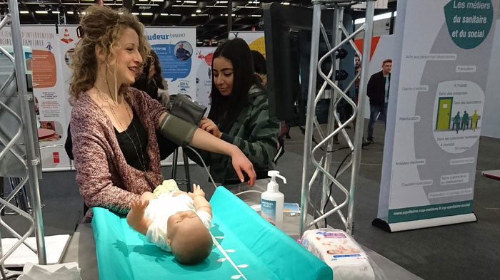 Une participante apprend à utiliser un tensiomètre lors d’un atelier interactif consacré aux métiers du sanitaire et social.