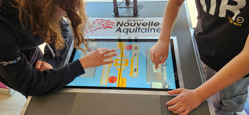 Deux jeunes utilisent une tablette tactile interactive pour explorer les métiers du transport et de la logistique dans le cadre d’un atelier numérique.
