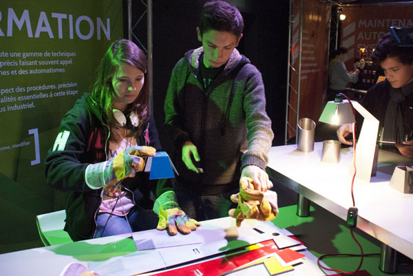 Deux jeunes participants manipulent des objets sur un atelier interactif lors de l’exposition « Secrets de fabrication » de Cap Métiers Nouvelle-Aquitaine.